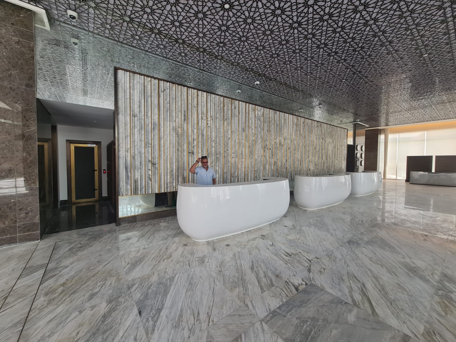Reception counters with marble wall fins and patterned ceiling