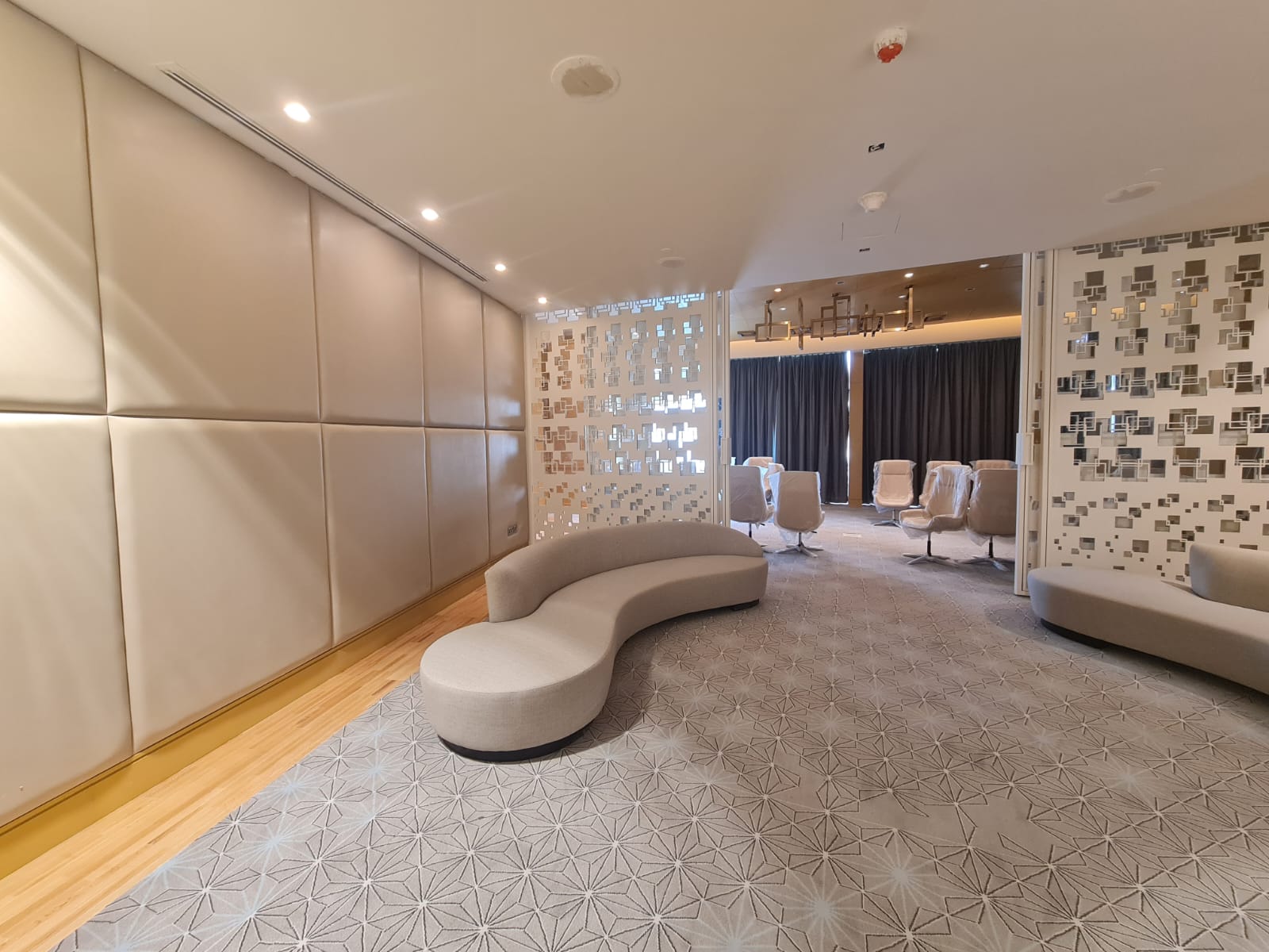 Soft lounge with wall panels, patterned carpet, and privacy screens