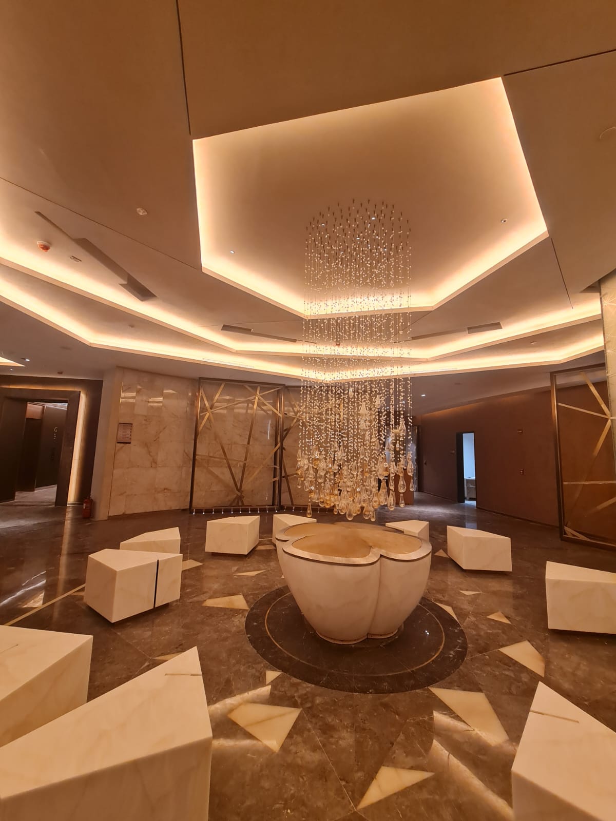 Warm lobby with layered ceiling light and central chandelier